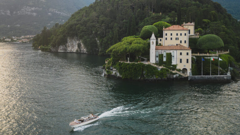 Villa del Balbianello on its wooded point, a motorboat crossing Lake Como below, Matteo Cuzzola Photography