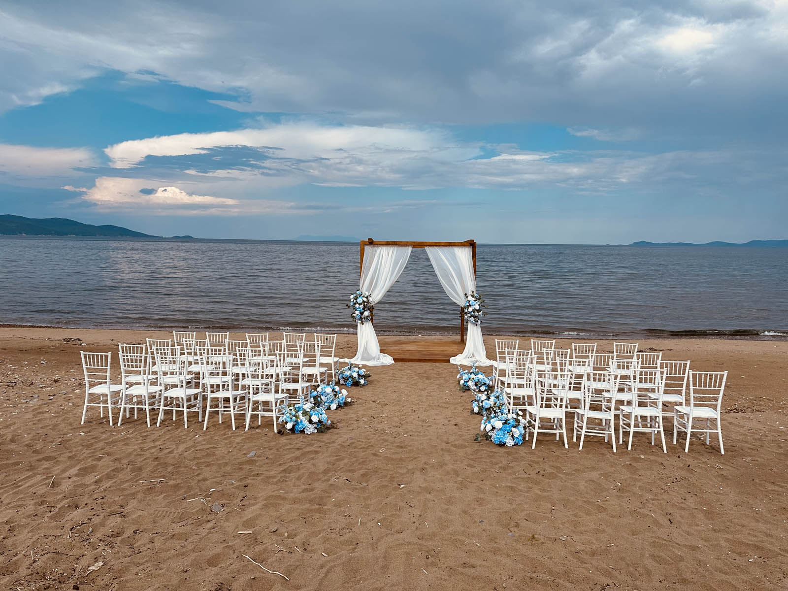 Beach ceremony chairs and arch on the sand, Mazal Weddings