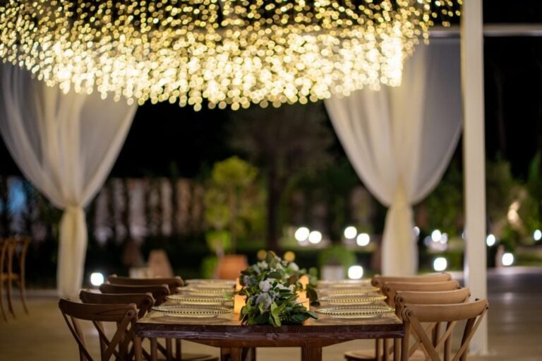 A draped pavilion with a canopy of fairy lights over a dining table at night, Mazal Weddings