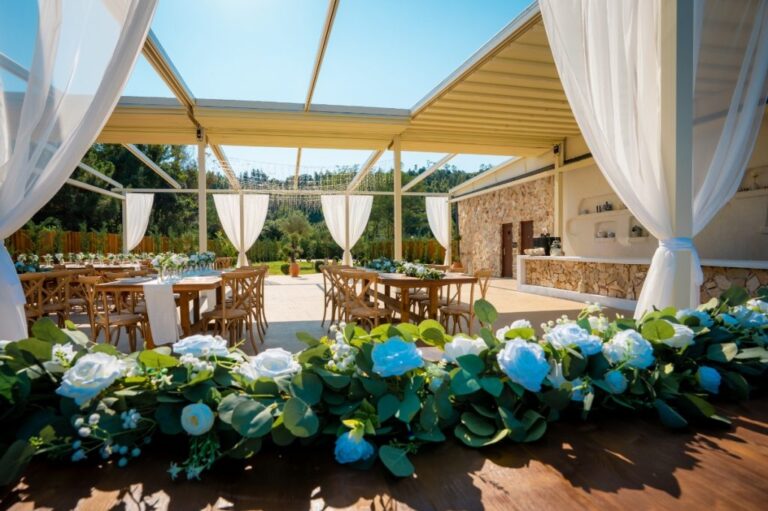 A covered terrace with long tables and a garland of white and blue flowers, Mazal Weddings