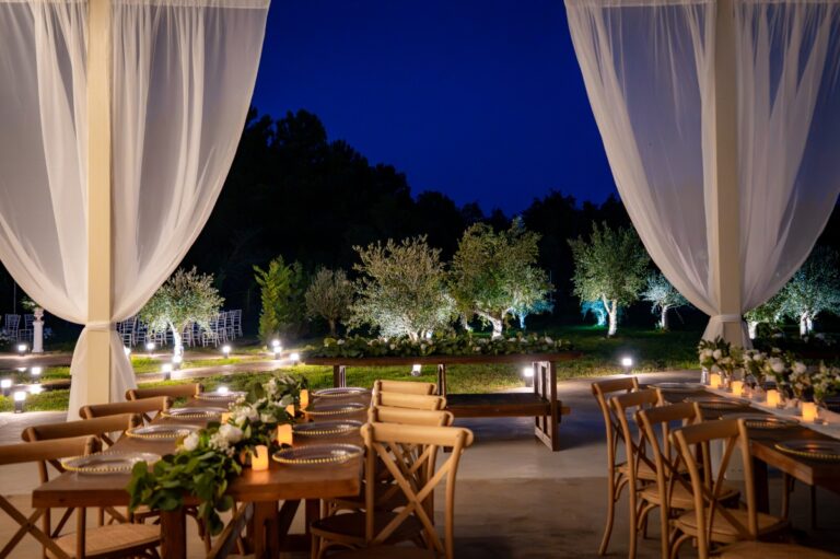 White drapes over rows of tables at night in the lit garden, Mazal Weddings