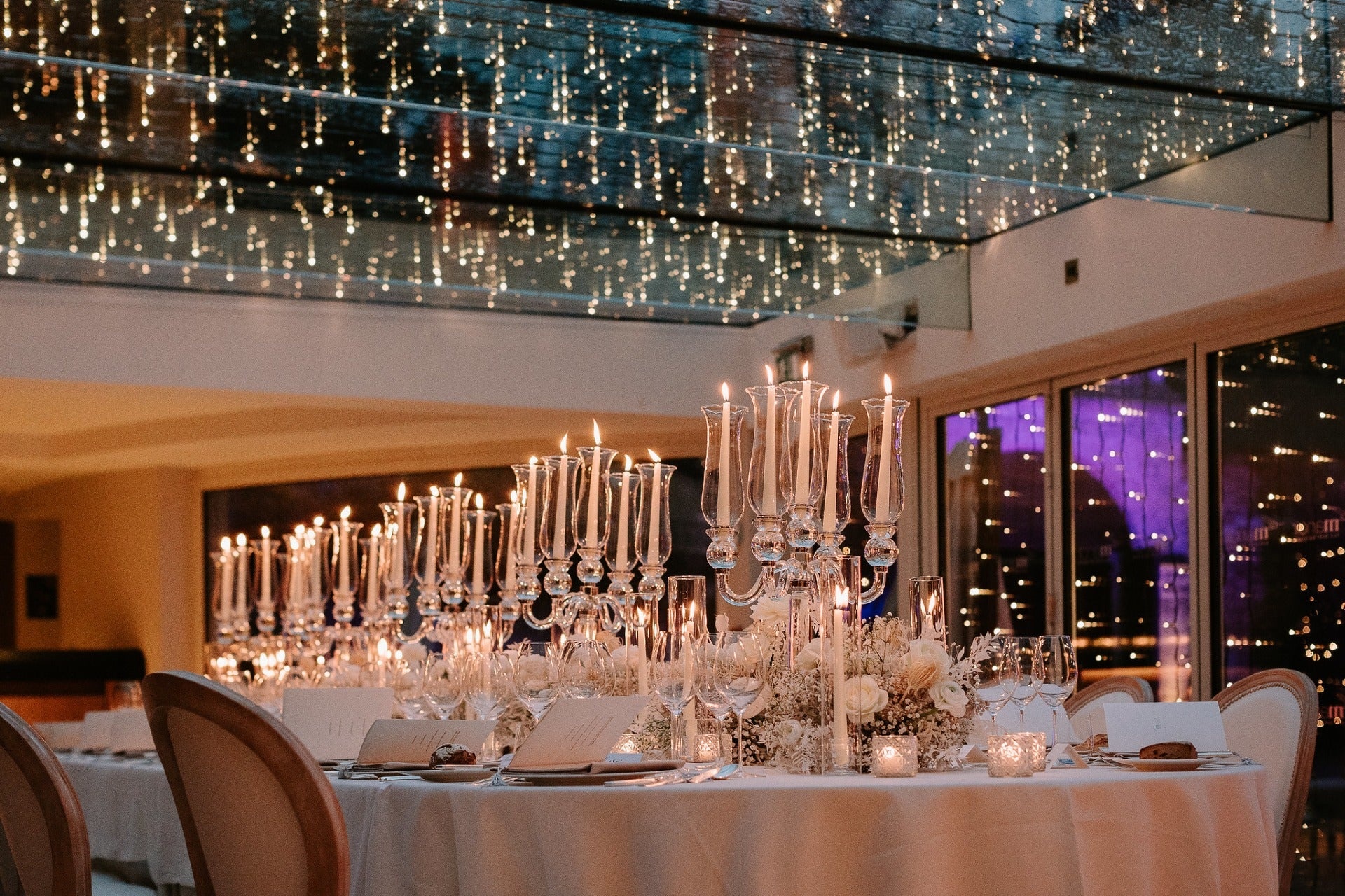 A candlelit dinner table set beneath a canopy of fairy lights, Le Manoir aux Quat'Saisons. Photography by Harper Evans, McQueens Flowers