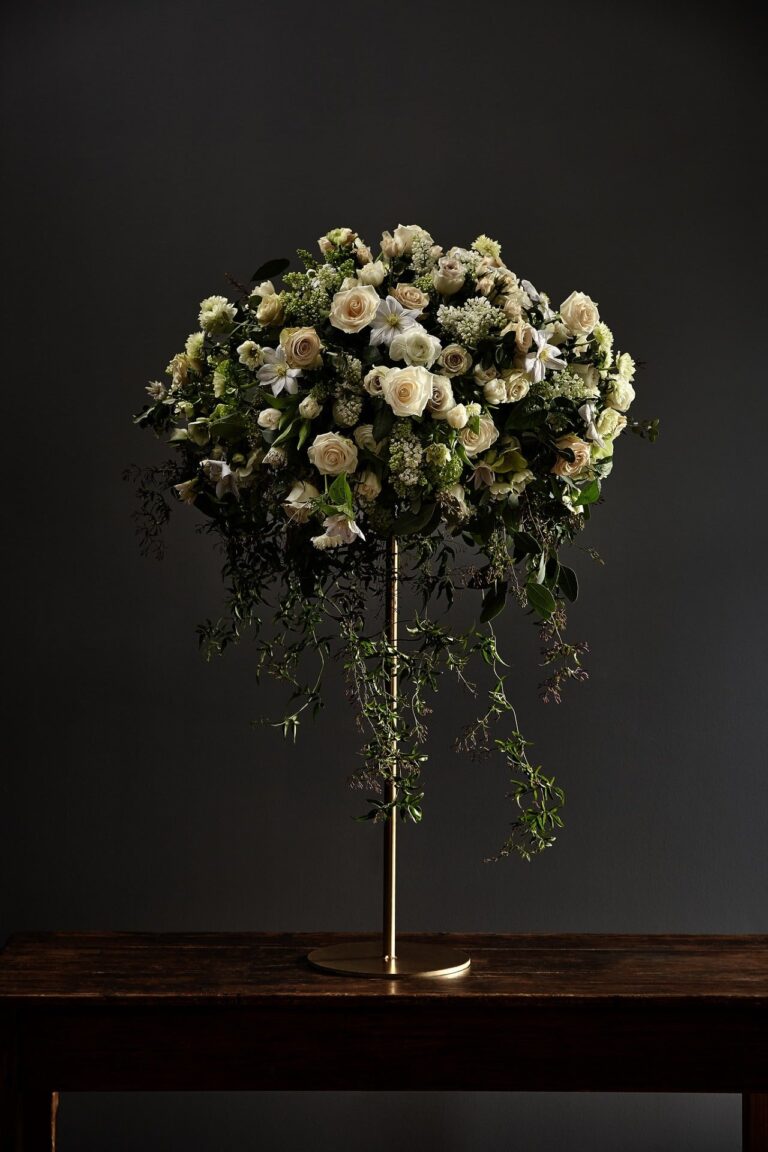 A loose, seasonal arrangement of poppy and ranunculus in a glass compote, McQueens Flowers