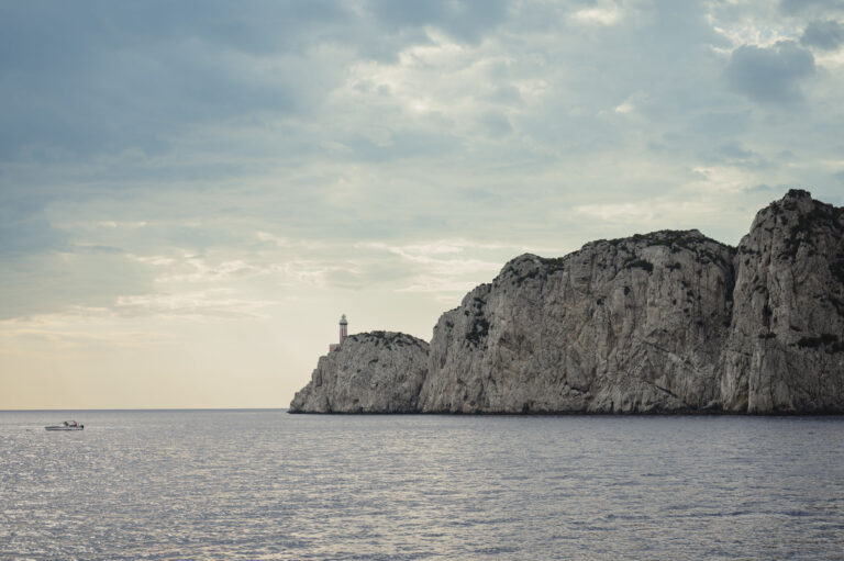 The Punta Carena lighthouse and cliffs on Capri's western coast, a small boat on the water, Med inStyle