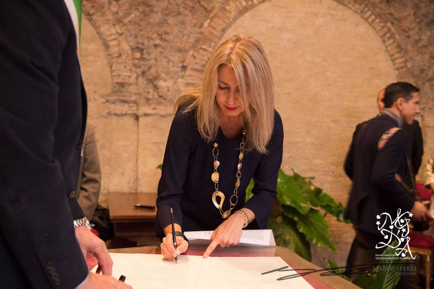 Monica witnesses a civil wedding register at a marble table beneath a brick vaulted arch, MGDA Events