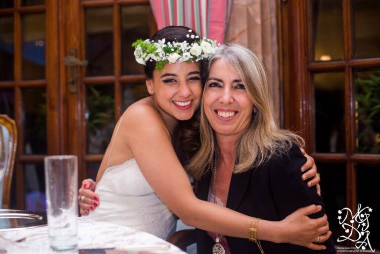 Monica and a groom dance with raised, joined hands in a torch-lit loggia hung with citrus trees, MGDA Events