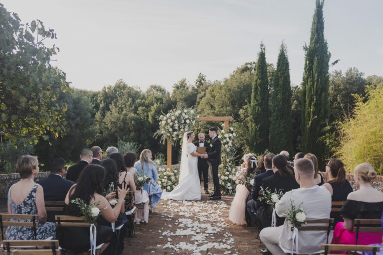 An outdoor ceremony at Borgo Gallinaio, guests seated on a petal-strewn terrace beneath tall cypresses, Michele Monasta Photography