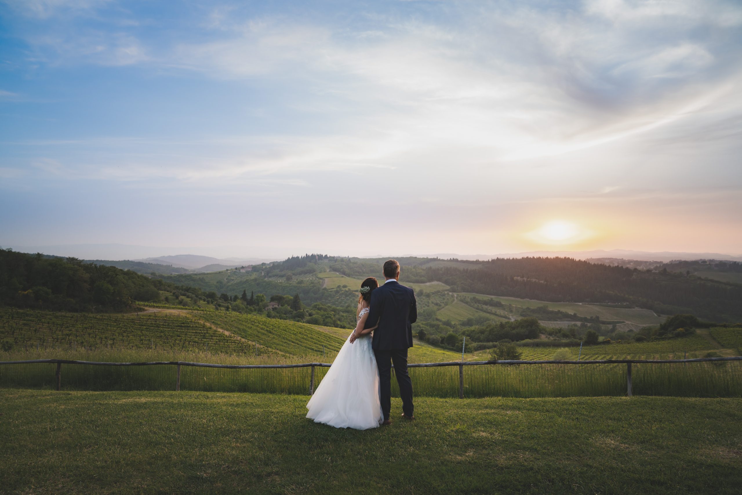The couple at sunset above the vineyards of the Chianti hills, on a wedding day that began at the Church of Argiano in San Casciano in Val di Pesa, Michele Monasta Photography