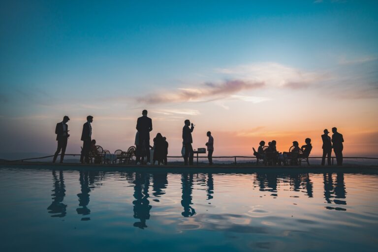 Guests silhouetted beside a pool at sunset during a reception in the Chianti countryside, Michele Monasta Photography