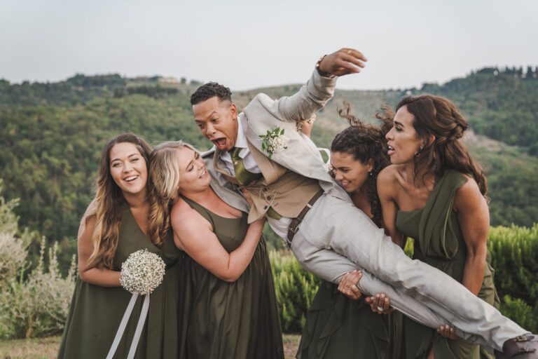 The bridesmaids lift the groom off his feet for a group photograph above the hills, Michele Monasta Photography
