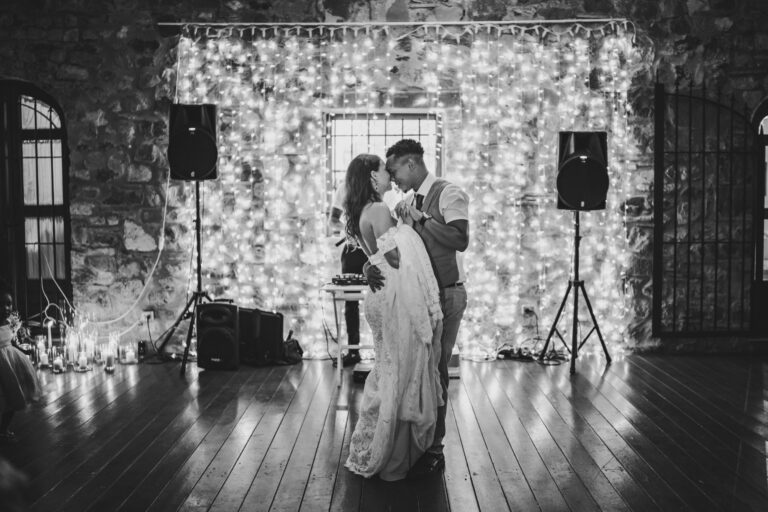 The first dance in front of a curtain of fairy lights, in black and white, Michele Monasta Photography