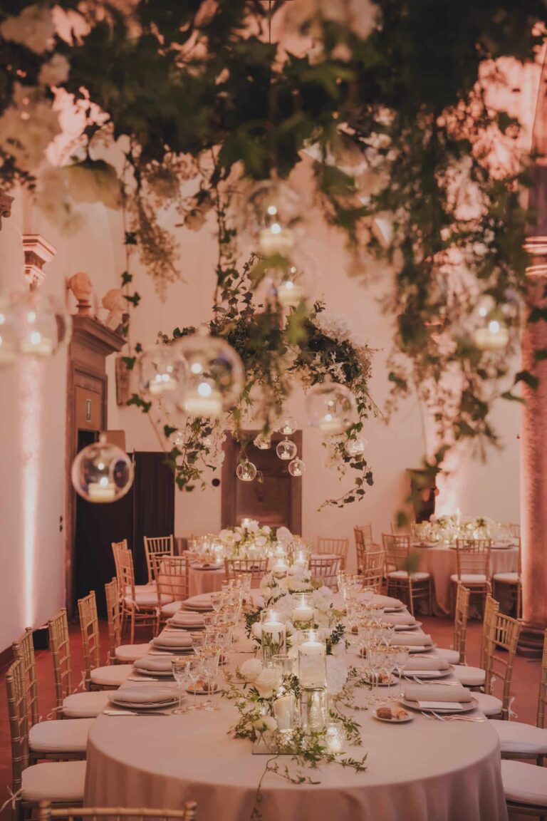 Dinner tables beneath hanging greenery and glass candle globes at Villa Le Corti, Michele Monasta Photography