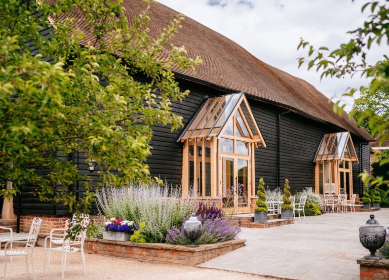 The Great Barn exterior, black weatherboard with an oak porch and lavender borders, Micklefield Hall
