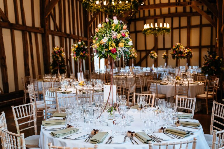 The Great Barn interior, round tables with tall pedestal florals, Micklefield Hall