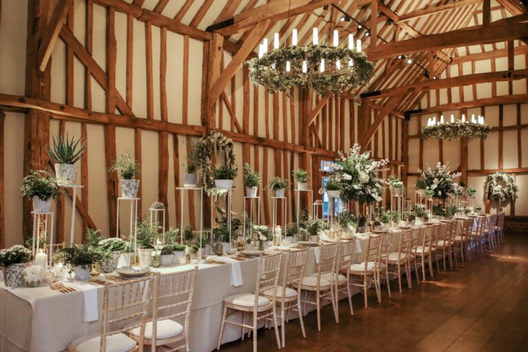 The Great Barn interior, a long table dressed with tall greenery, Micklefield Hall