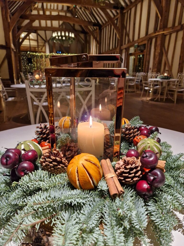 The Great Barn at Christmas, a candle and fruit centrepiece in the foreground, Micklefield Hall