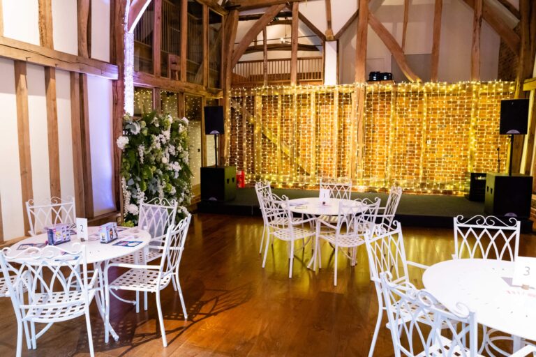 The Great Barn with a fairy-light curtain backdrop and cafe seating, Micklefield Hall