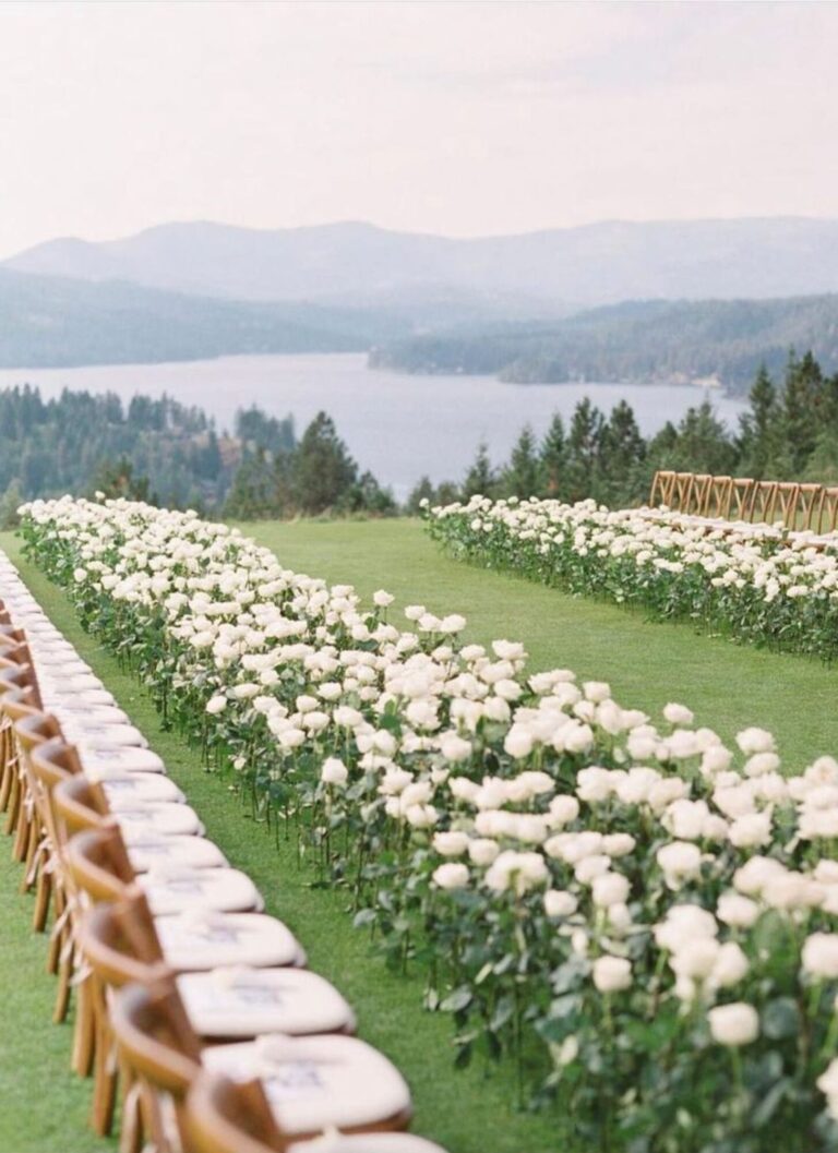 A lawn aisle edged with white flowers above a lake and mountains, Mindy Weiss Party Consultants