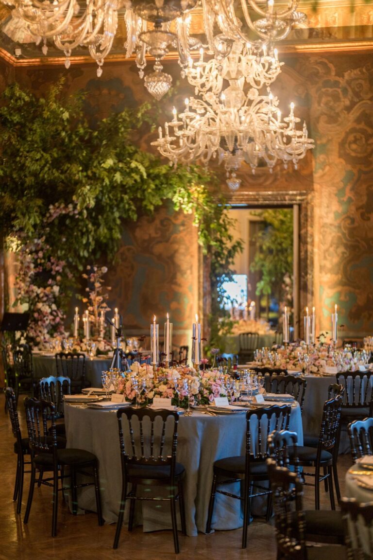 A reception under a chandelier with round tables and pink floral centrepieces, Mindy Weiss Party Consultants