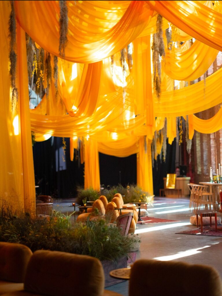 Saffron-orange fabric draped from the ceiling of a reception space, Mindy Weiss Party Consultants