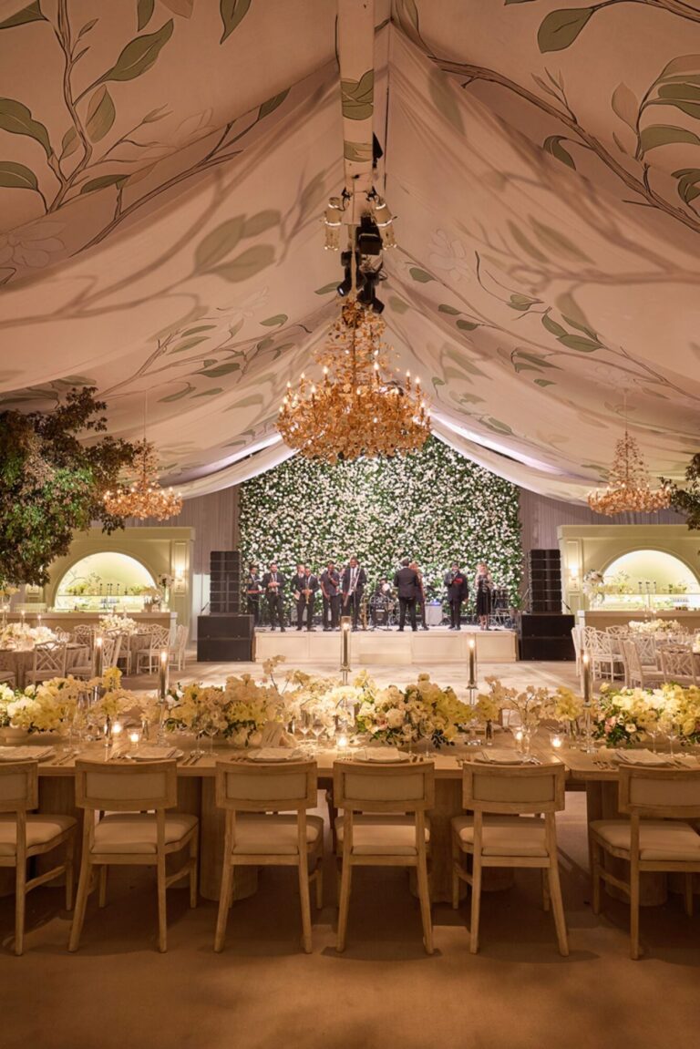 A tented reception with painted ceiling, chandelier and long wooden tables, Mindy Weiss Party Consultants