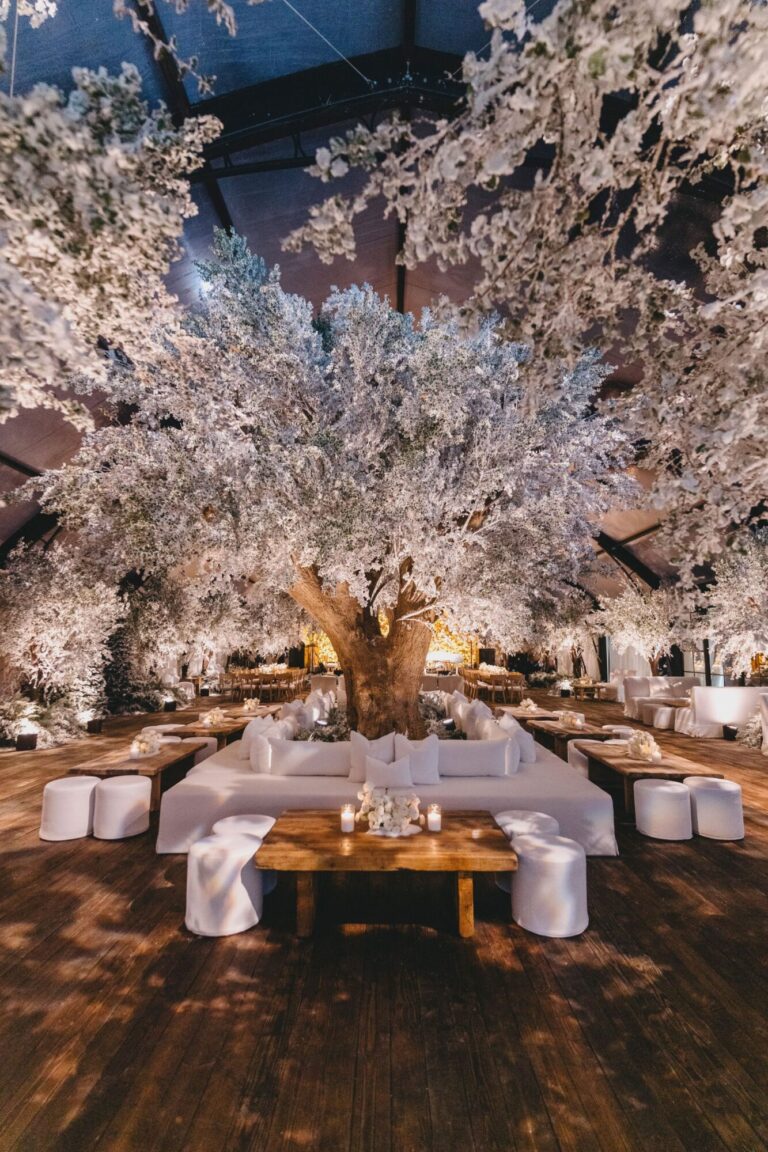 A lounge of white sofas beneath a blossom-covered olive tree, Mindy Weiss Party Consultants
