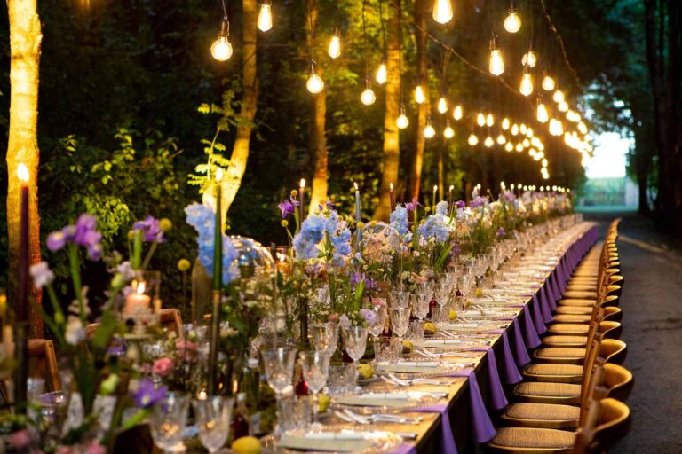 A long imperial table under strung bulbs, a purple runner and gold chairs, Mirko Zago, Sparkling Weddings and Events