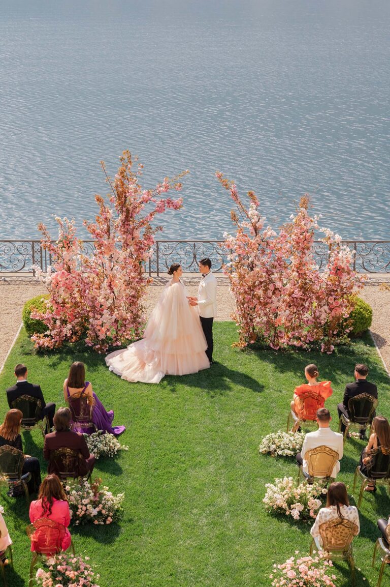 Lawn ceremony beside Lake Como with pink floral installations at Villa Balbiano, Mitheo Events