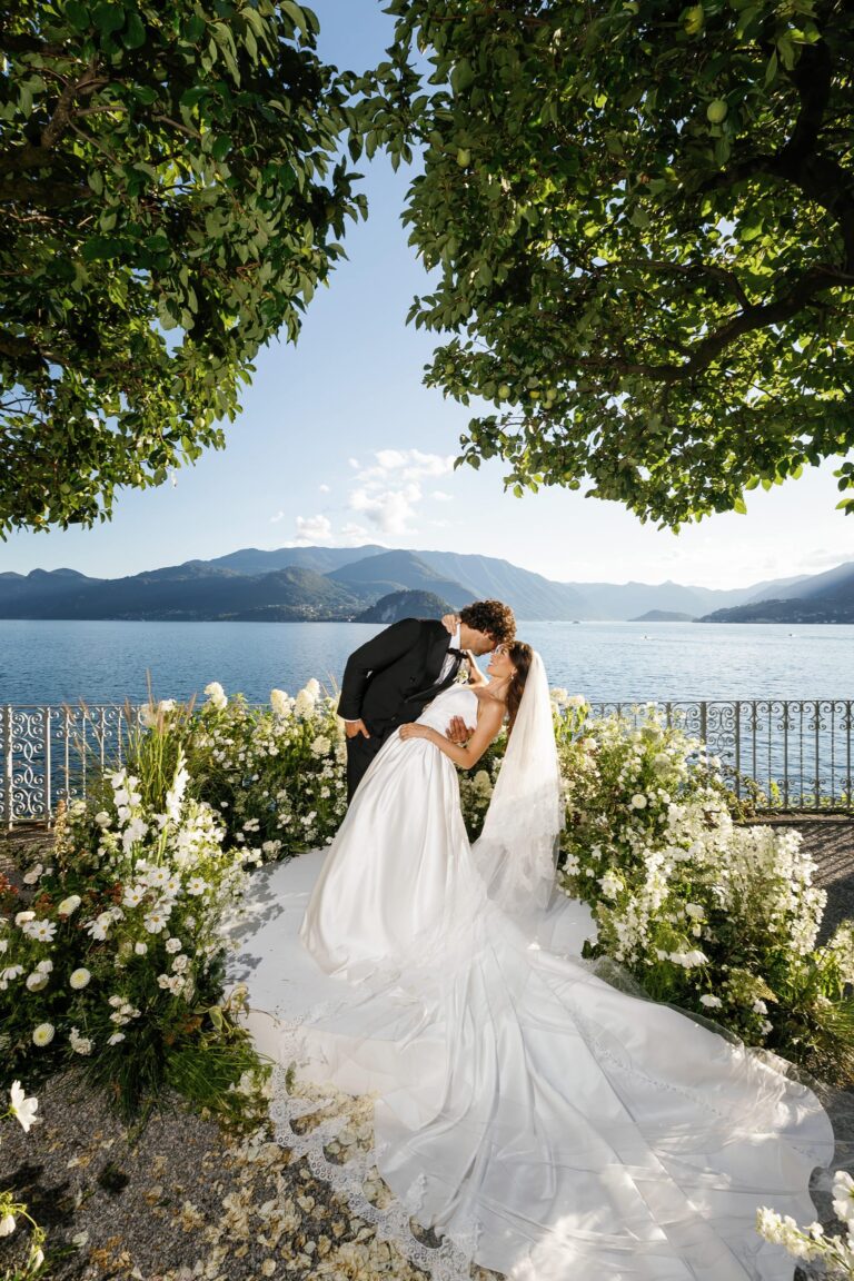 A couple kiss on a lakeside garden aisle in Varenna, Lake Como, Mitheo Events