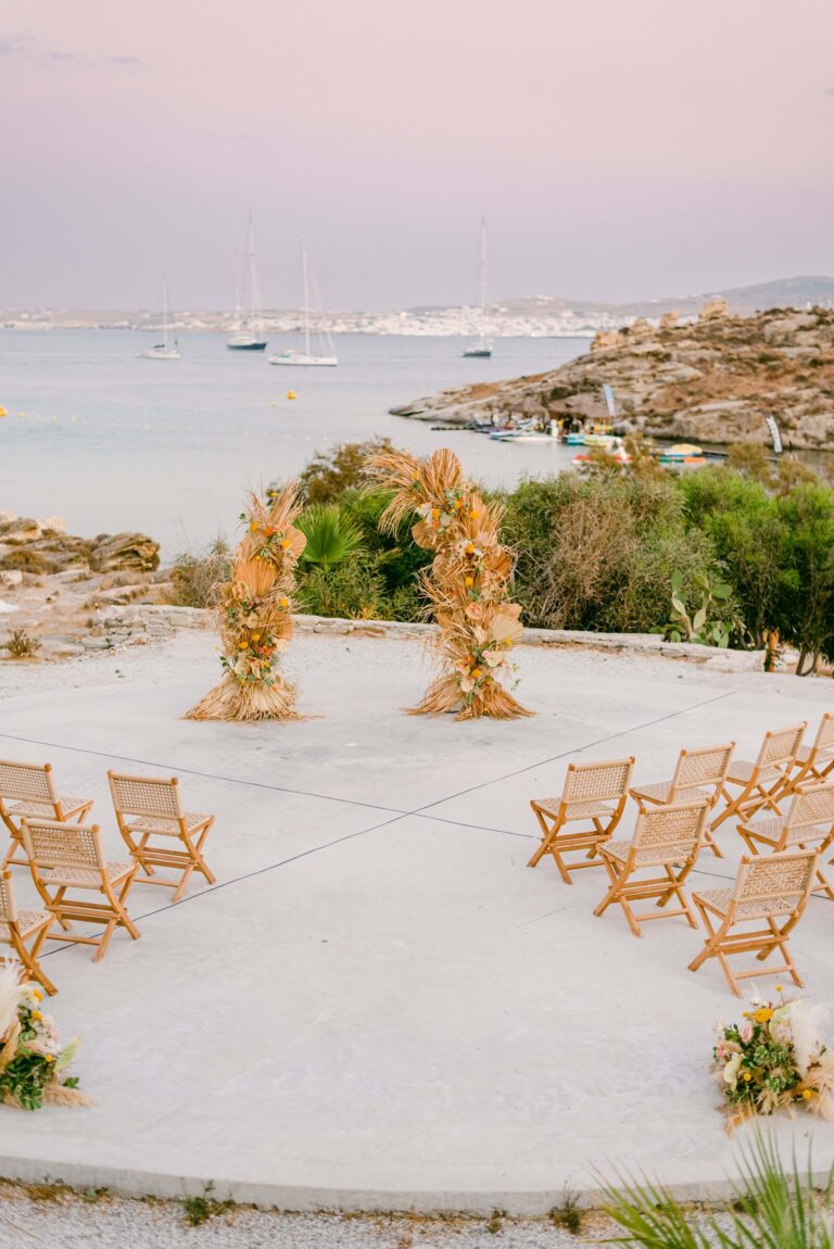 Seaside ceremony set-up with a dried floral arch in Paros, Mitheo Events