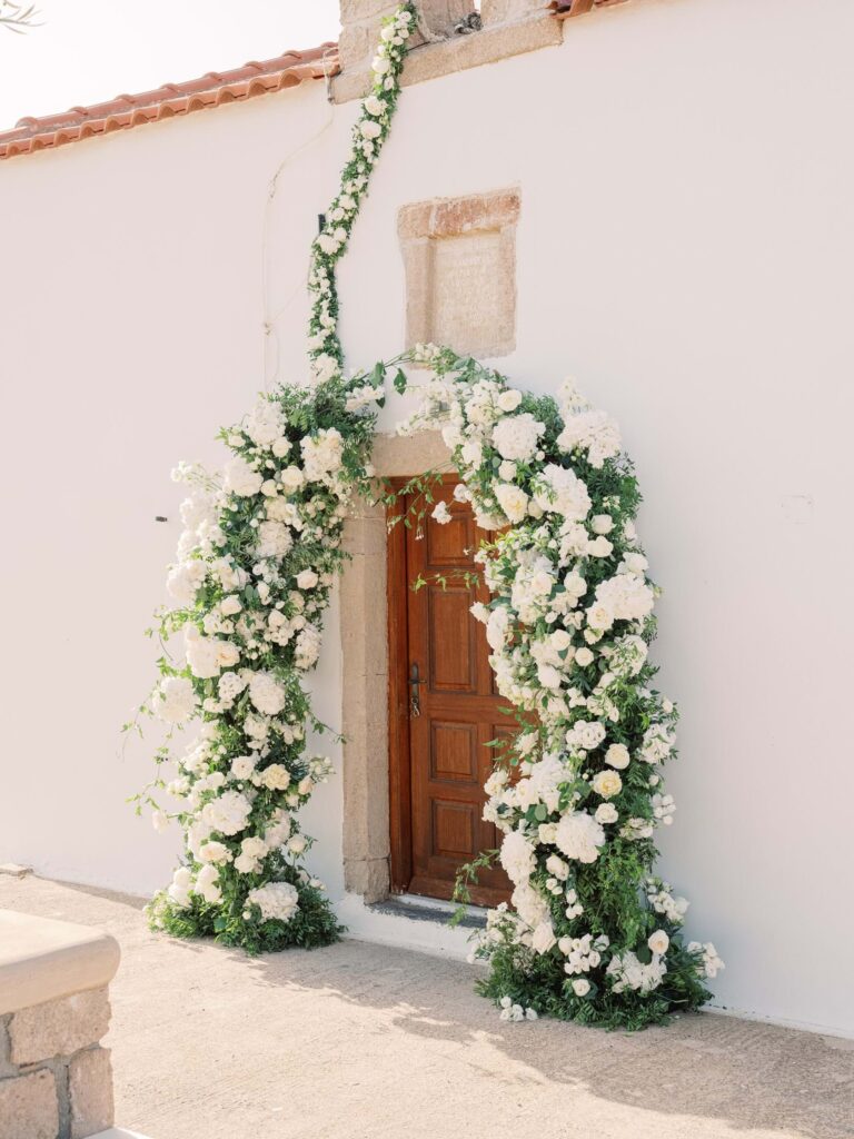 A chapel door framed by a flower arch in Elafonisos, Mitheo Events