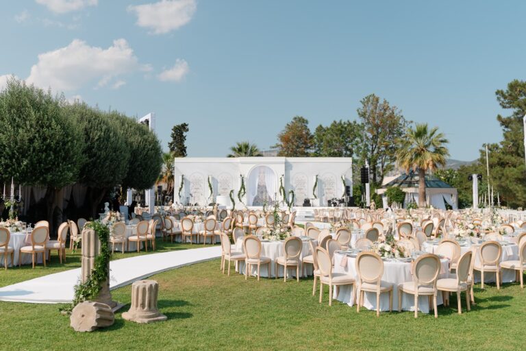 Round reception tables on a lawn beneath olive trees on the Athenian Riviera, Mitheo Events