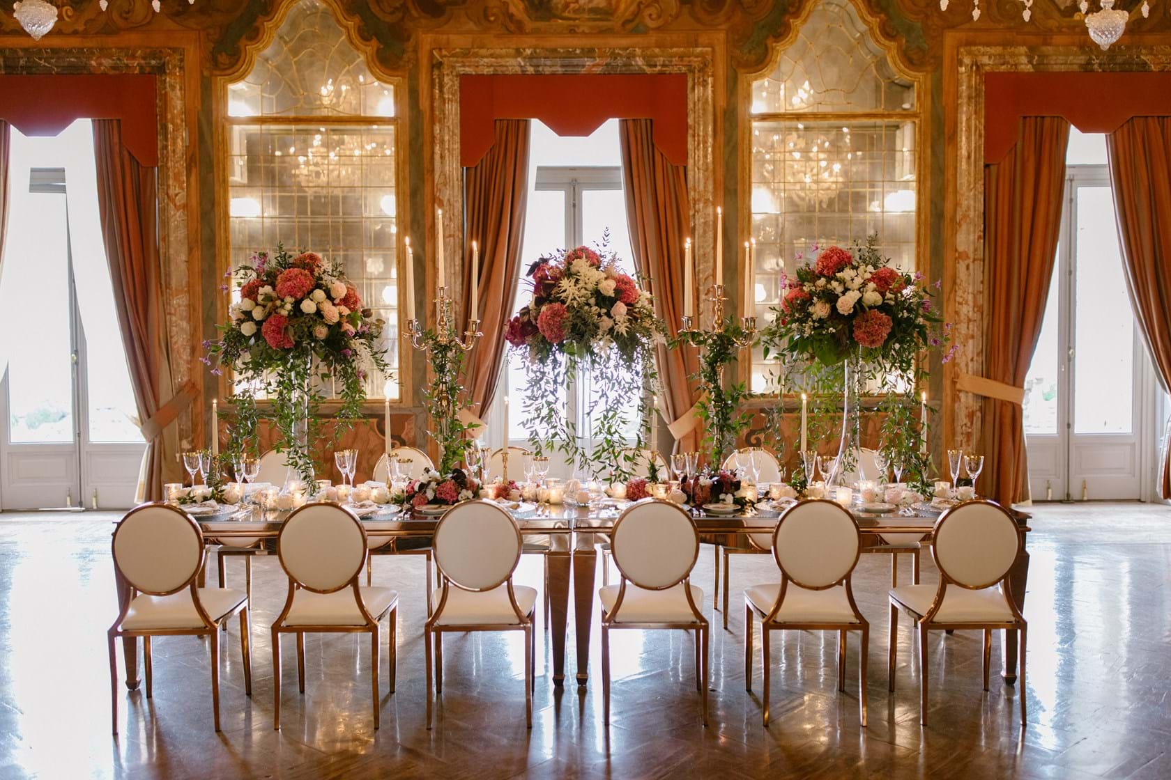 Reception table laid beneath chandeliers in a frescoed room at Villa Erba, Lake Como, Mitheo Events