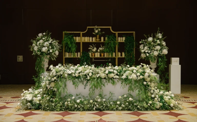 A flower-covered head table in a hotel ballroom at Costa Navarino, Mitheo Events