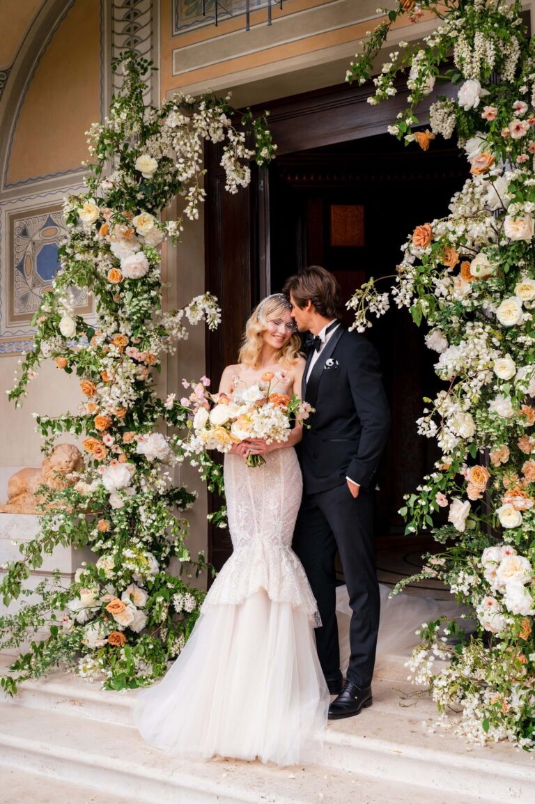 A couple framed by a flower arch at the entrance to Villa Clara, Rome, Mitheo Events