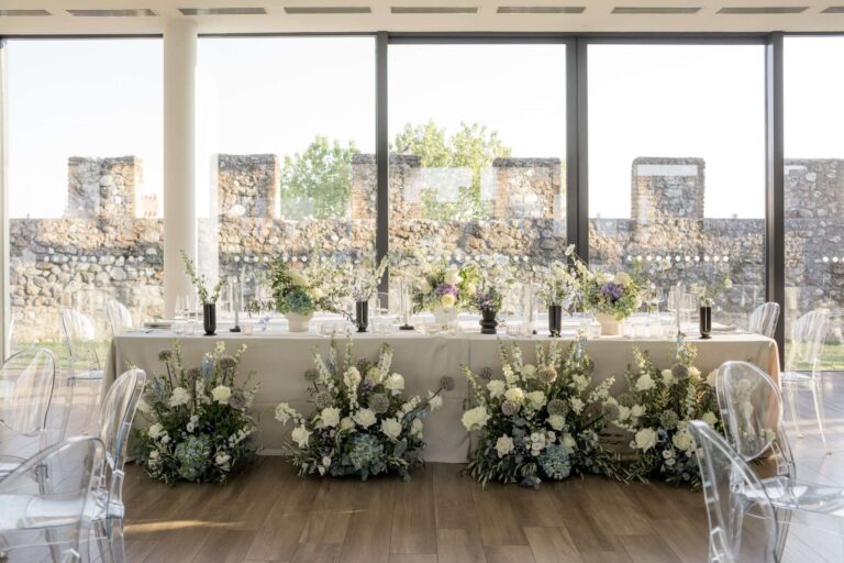 Head table with white floral banks in front of crenellated walls, a Lake Garda wedding, More Than Weddings