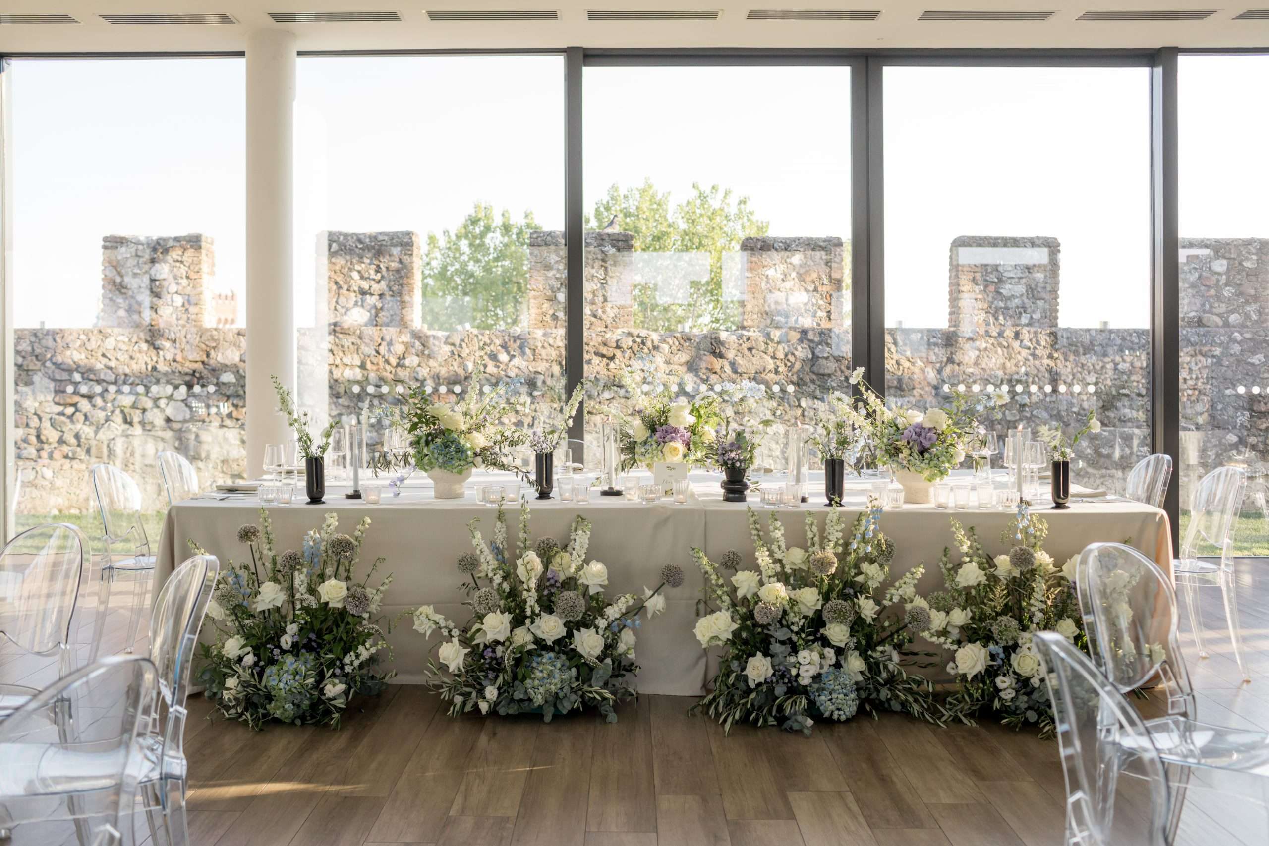 Head table with white floral banks in front of crenellated walls, a Lake Garda wedding, More Than Weddings