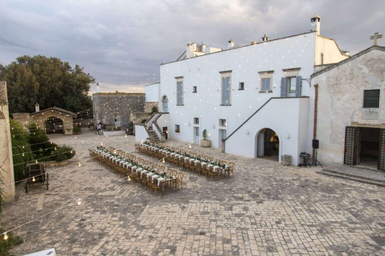 Reception tables in the paved courtyard of a white masseria in Apulia, More Than Weddings