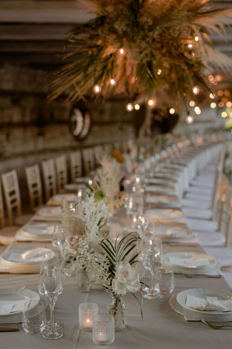 Long candlelit table under a hanging pampas and dried-flower installation, Verona, More Than Weddings