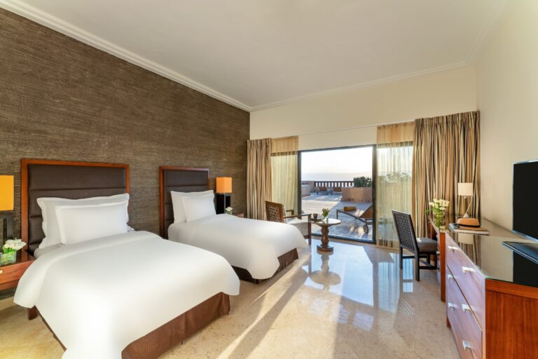 Twin beds with sliding doors to a terrace, Mövenpick Resort & Spa Dead Sea