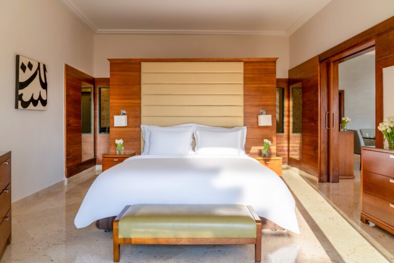 Suite bedroom with king bed and timber headboard wall, Mövenpick Resort & Spa Dead Sea