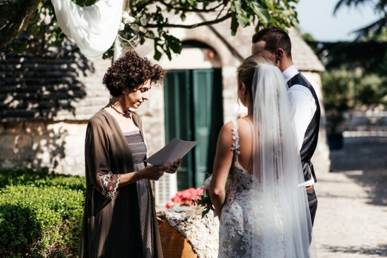 A celebrant reading to the couple in a courtyard beside a trullo, Puglia, Mr and Mrs Wedding In Italy