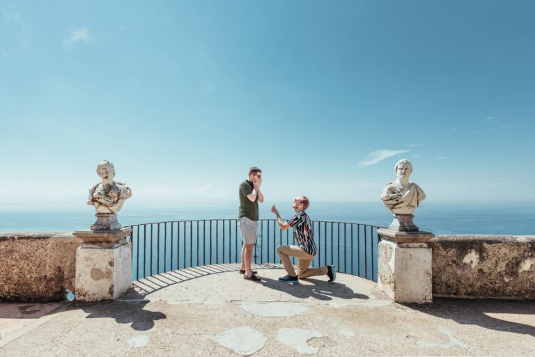 A proposal on a belvedere lined with marble busts, the open sea behind, Mr and Mrs Wedding In Italy