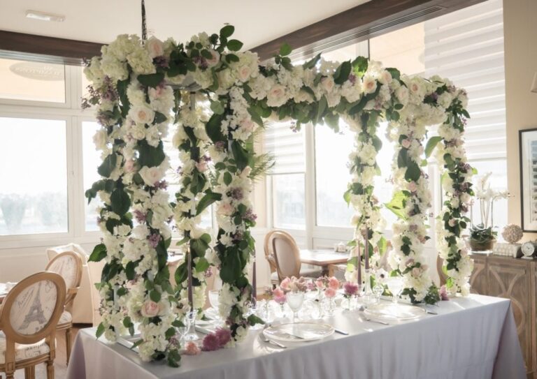 Floral arch of white and blush blooms over a head table at an indoor reception., My Dubai Wedding Planner