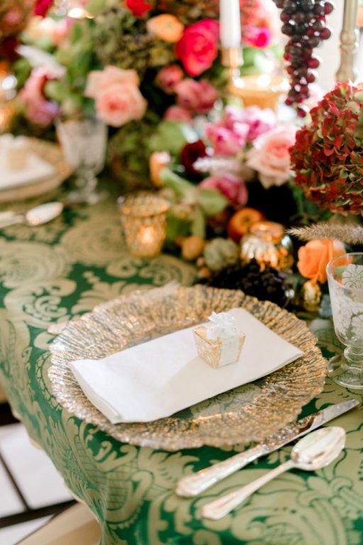 Place setting on green damask linen with a silver charger, favour box and seasonal flowers., My Dubai Wedding Planner