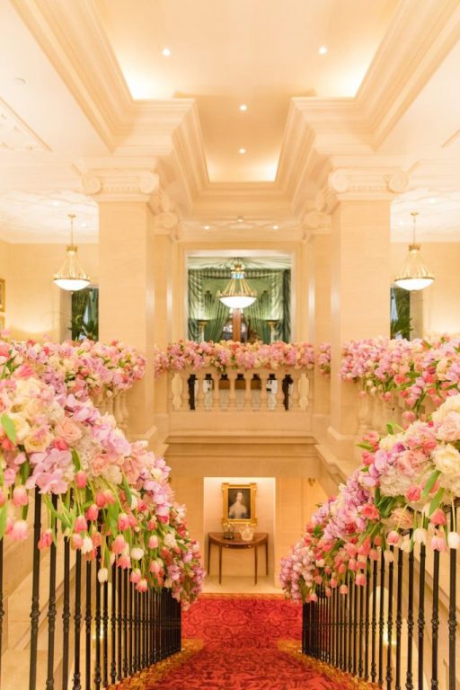 Staircase balustrade dressed with banks of pink tulips and roses leading to a red carpet., My Dubai Wedding Planner