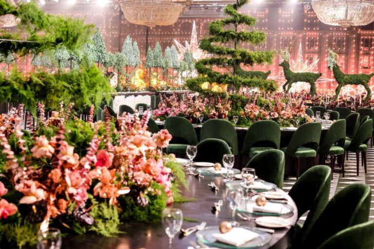 Table dressed with pink and orange flowers, topiary stags and an arched green setting behind, MY Event Design