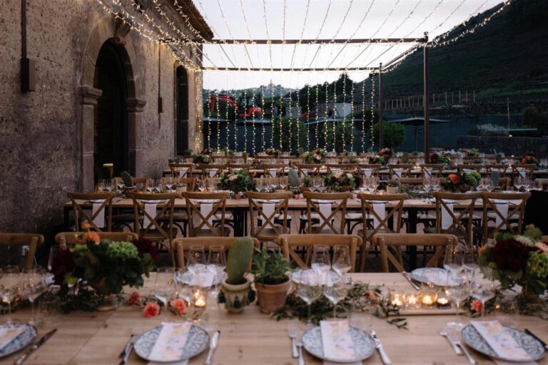 Long reception tables laid beneath a canopy of fairy lights strung from the stone building to the hillside at dusk, My Sicilian Wedding