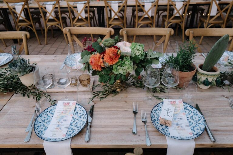 A reception table set with hand-painted Sicilian ceramics, Benanti wine glasses and a centrepiece of orange dahlias, My Sicilian Wedding