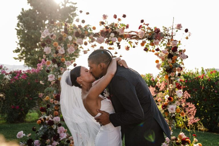 The kiss under a full floral arch, straight into the sun, My Sicily Wedding